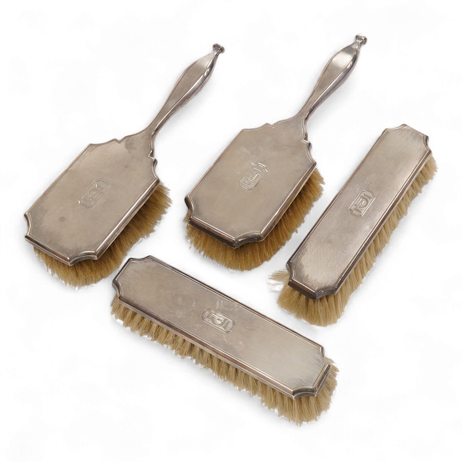 A 1930' matched engine turned silver mounted four piece dressing table brush set, William Comyns & Sons Ltd, London, 1933,36,38 & 39.